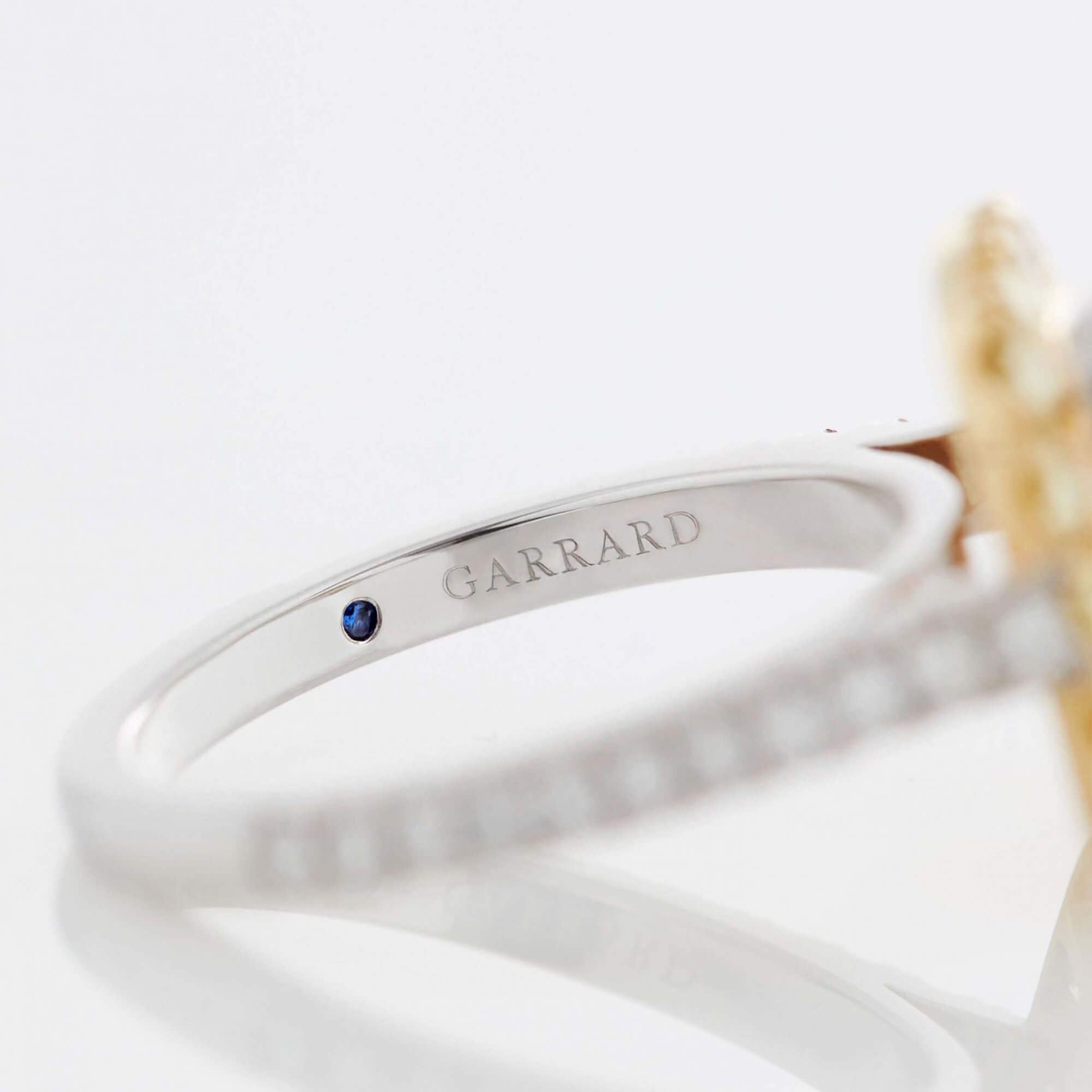 Close up of a Garrard engagement ring with a sapphire indide the diamond band mobile 1