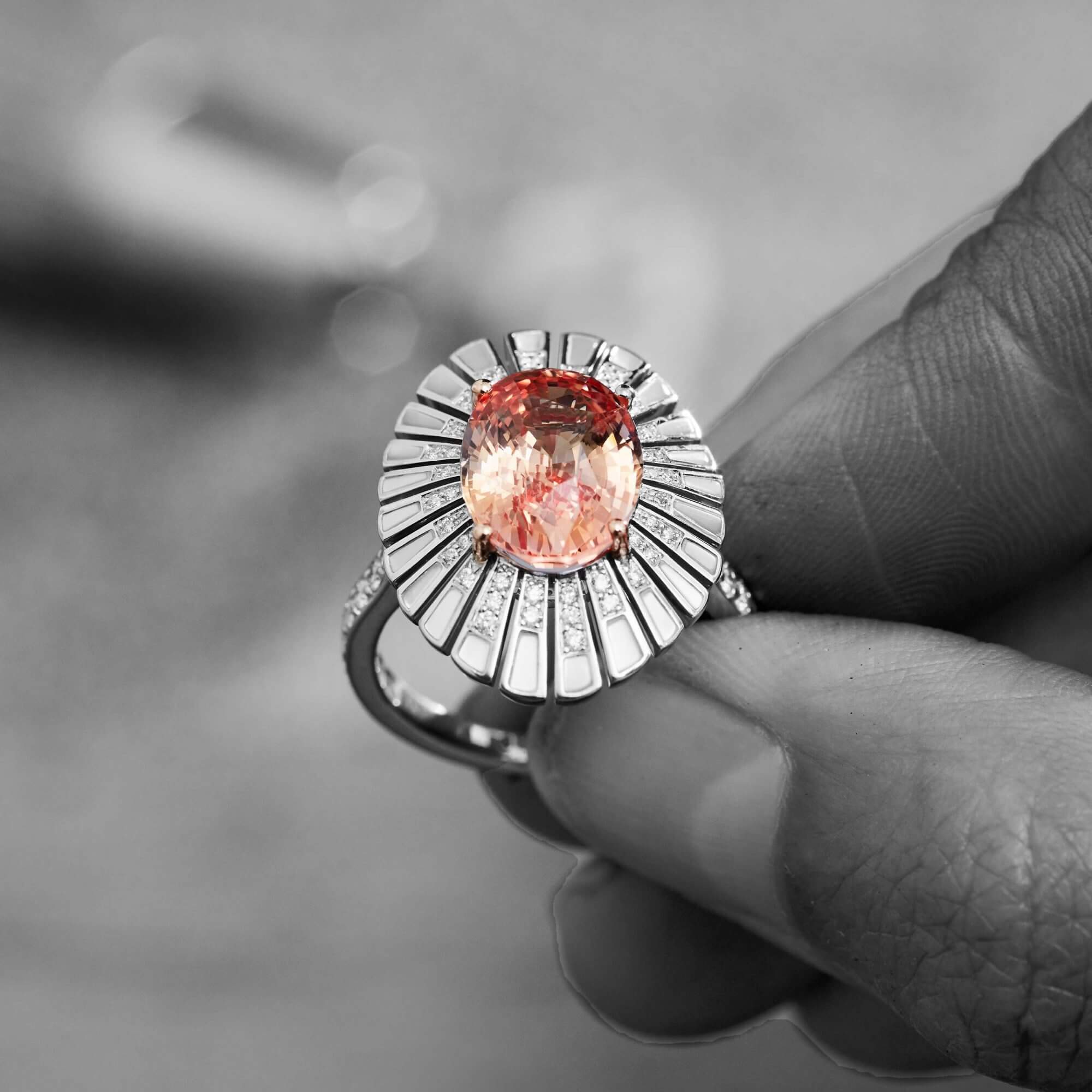 a craftsman holding a Garrard Jewelled Vault Padparadscha and diamond ring in the workshop