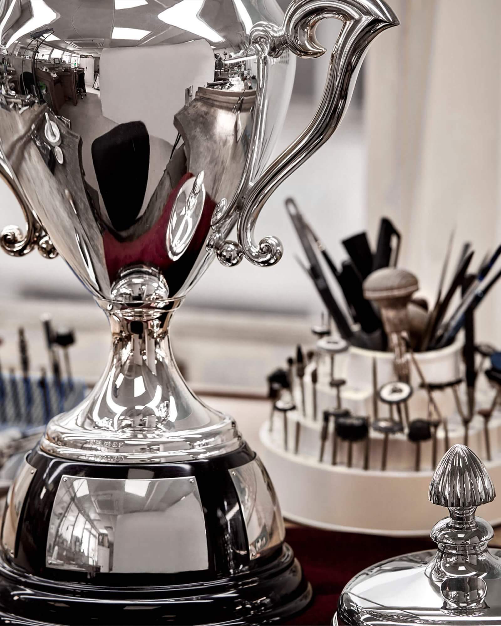reflections of a workbench in a polished silver Garrard sporting trophy