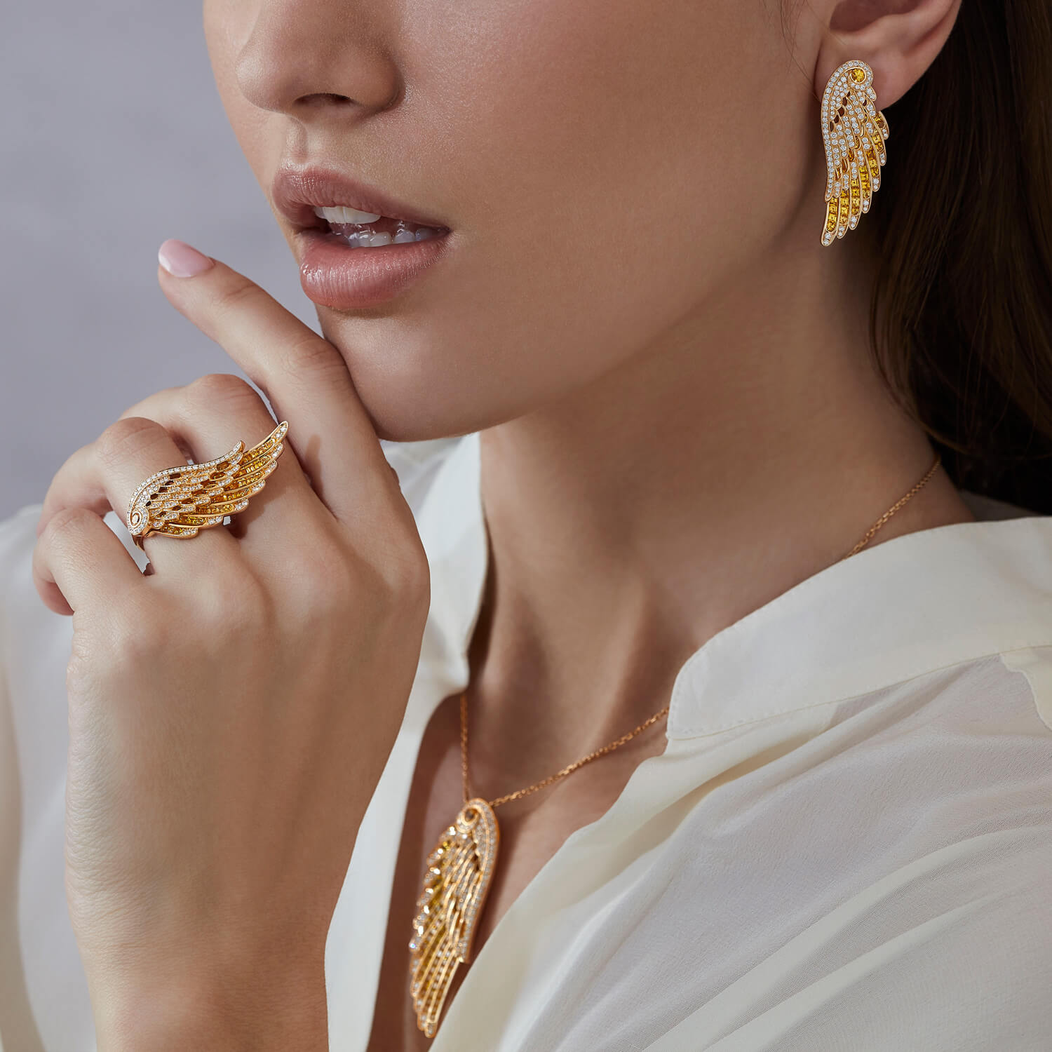 Model wears Garrard Wings Embrace jewellery collection Yellow Sapphire and Diamond Ear Climbers pendant and ring In 18ct Yellow Gold