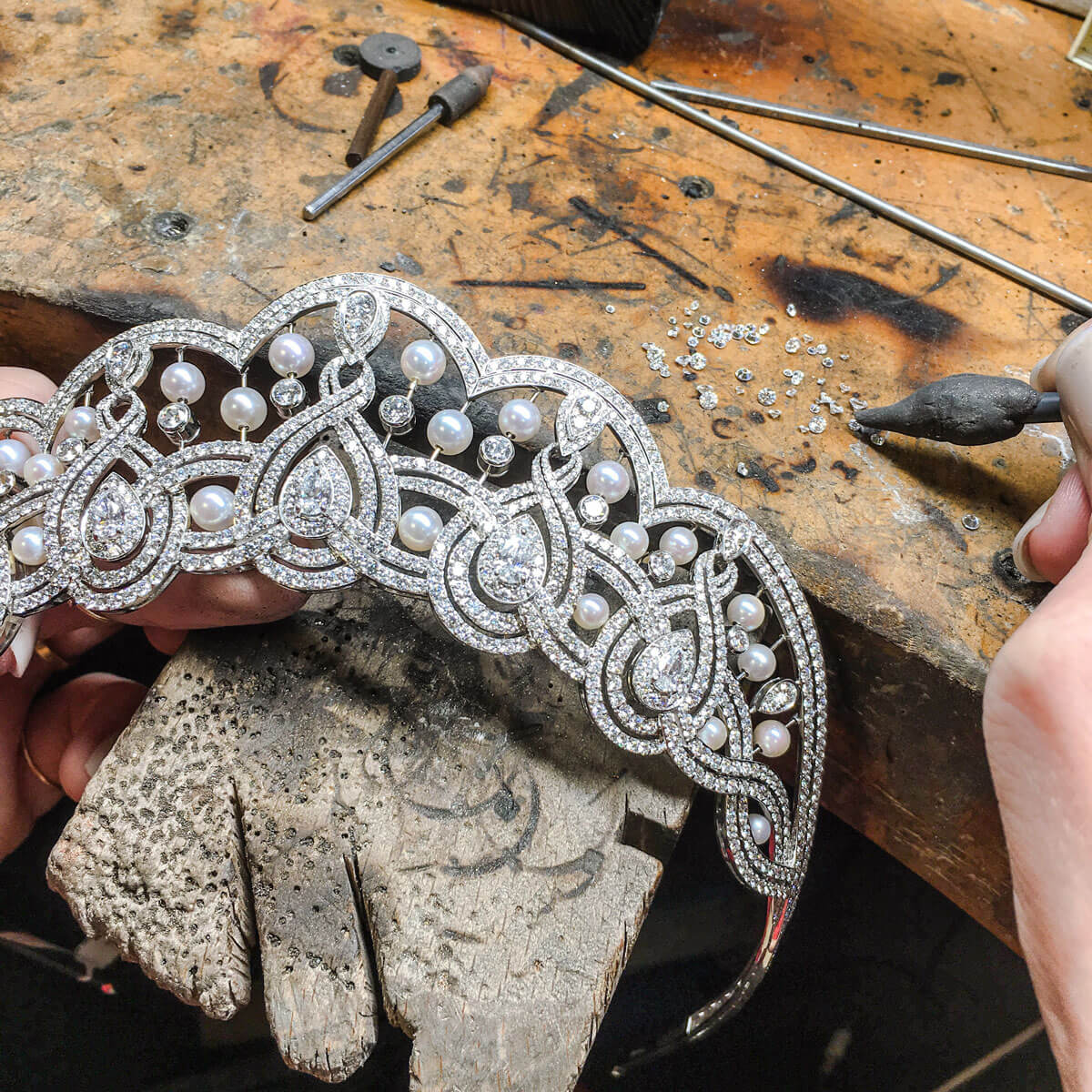 close up of a Garrard craftsman setting the Garland diamond and pearl Tiara in the Garrard London Workshop